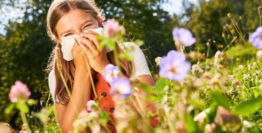 Child blowing nose in field of flowers